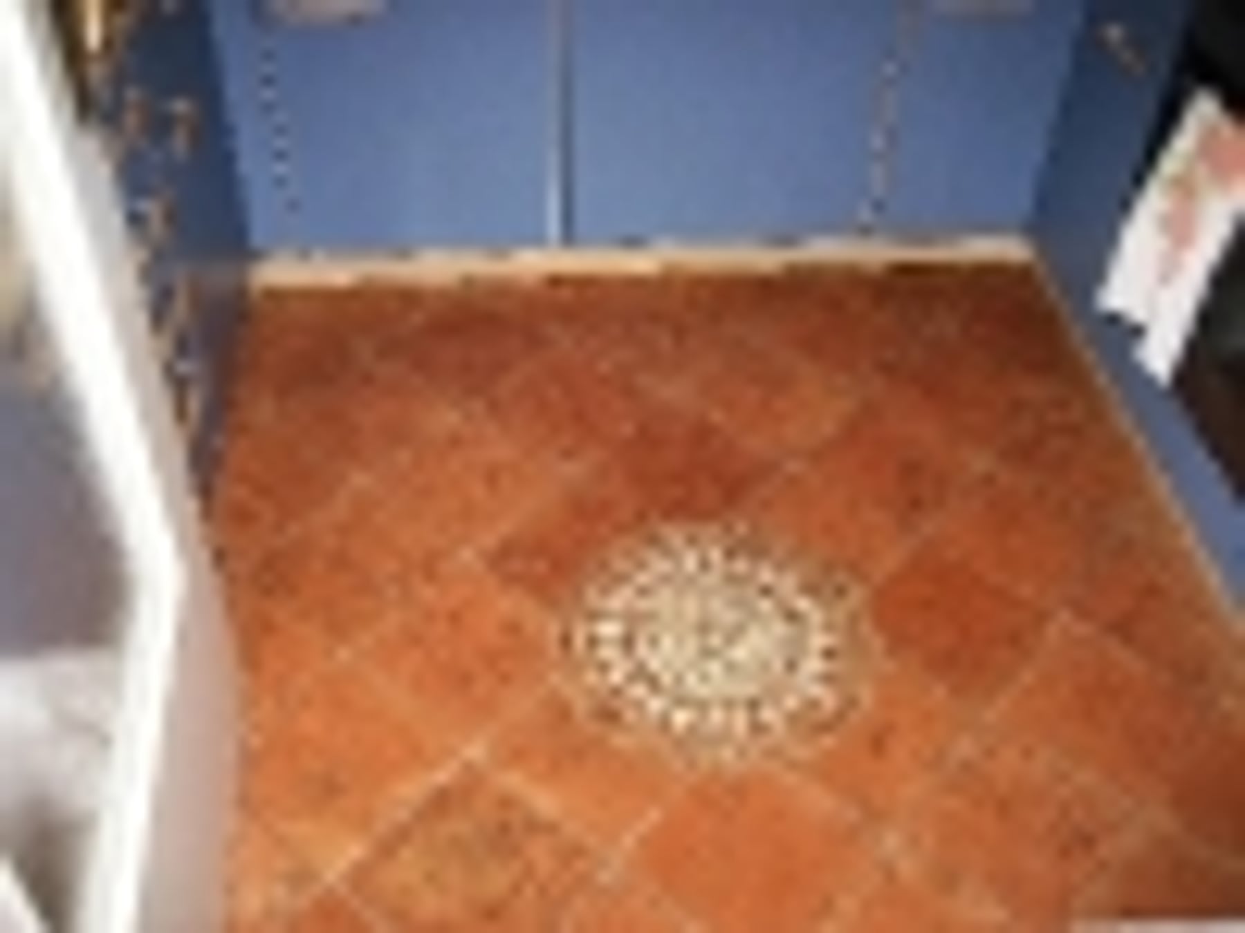 Fliesenboden mit Ornament-Mosaik und blauen Wänden